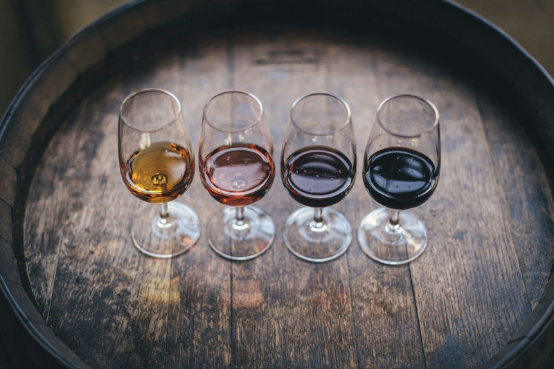 Four wine glasses on a rustic barrel, showcasing wine variety