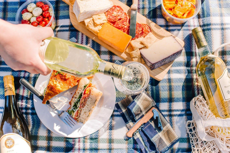 Pouring V. Sattui white wine at a picnic with sandwiches and cheese.